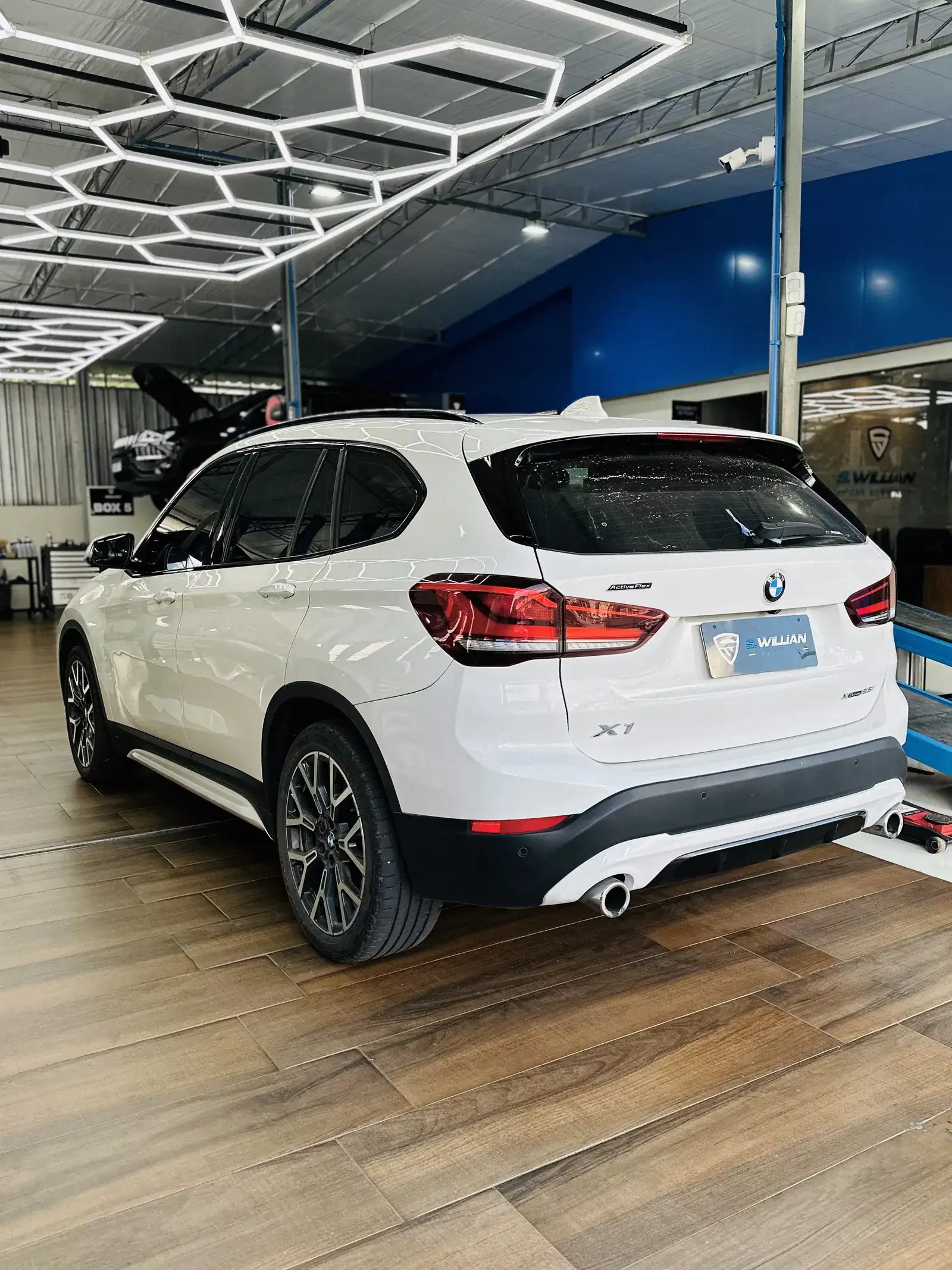 BMW X1 branco visto de trás, sob o teto hexagonal de LED