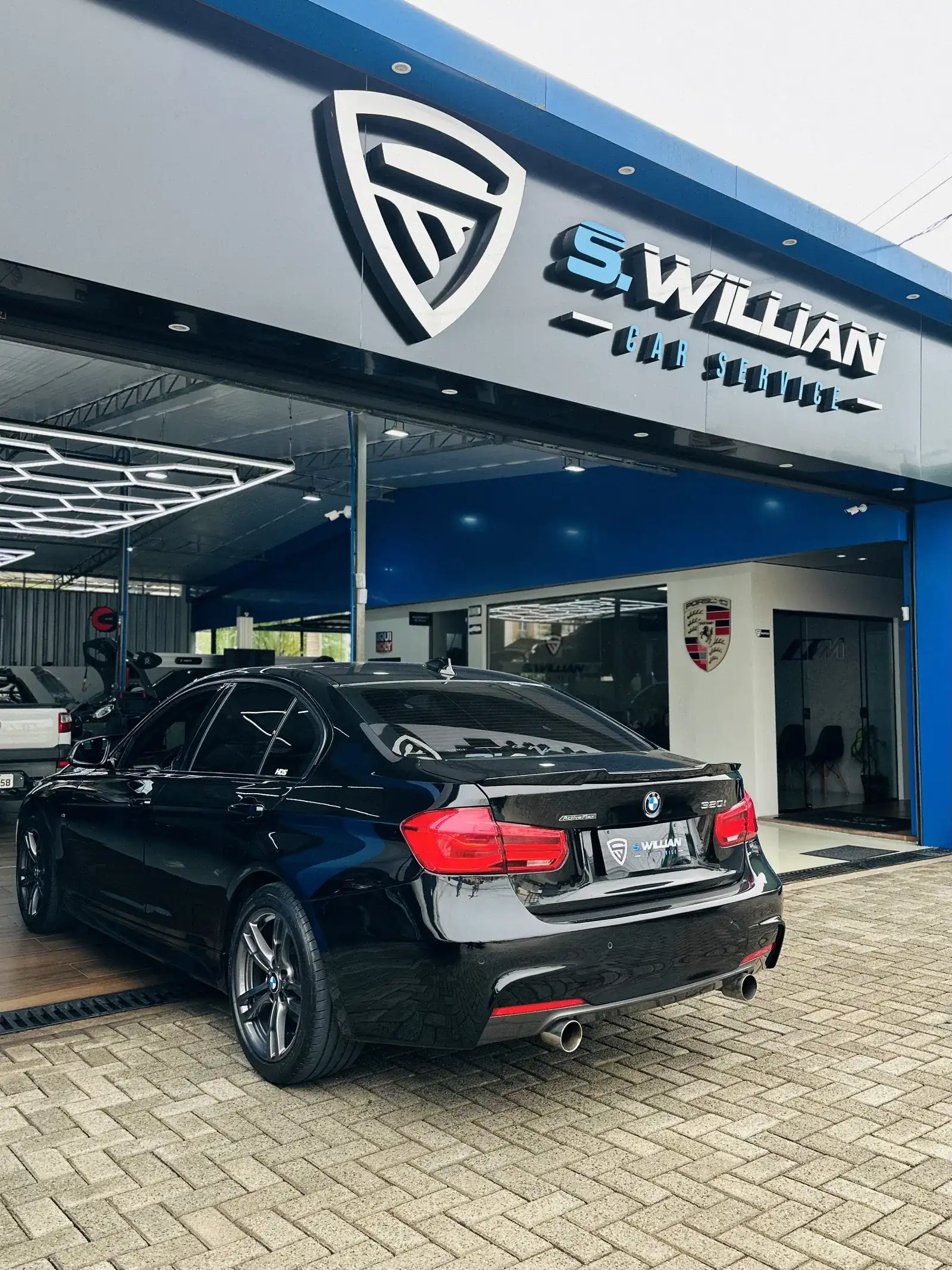 Fachada da S. Willian Car Service com o letreiro da oficina e um BMW 320i estacionado na calçada