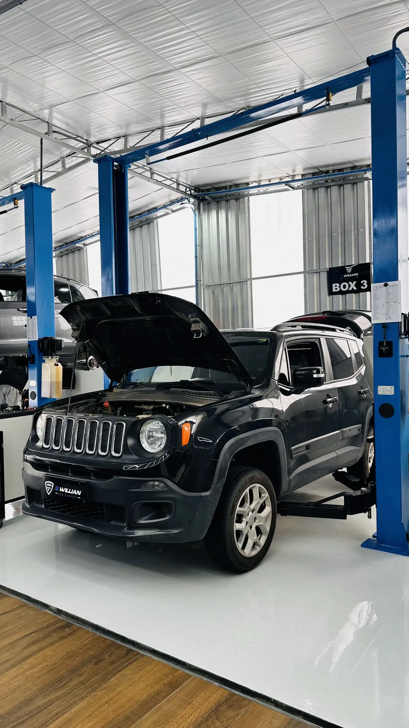 Jeep Renegade verde com o capô aberto no boxe 3