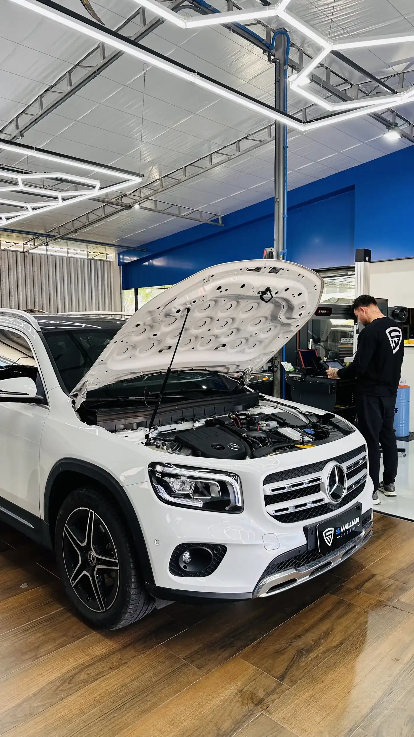 Mercedes-Benz GLB com o capô aberto, técnico ao fundo