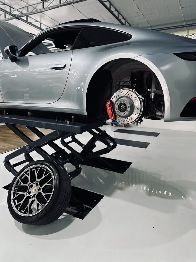 Detalhe da roda e do disco de freio de um Porsche 911 no elevador
