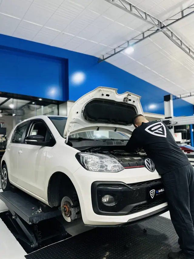 Técnico debruçado sobre o motor de um Volkswagen Up